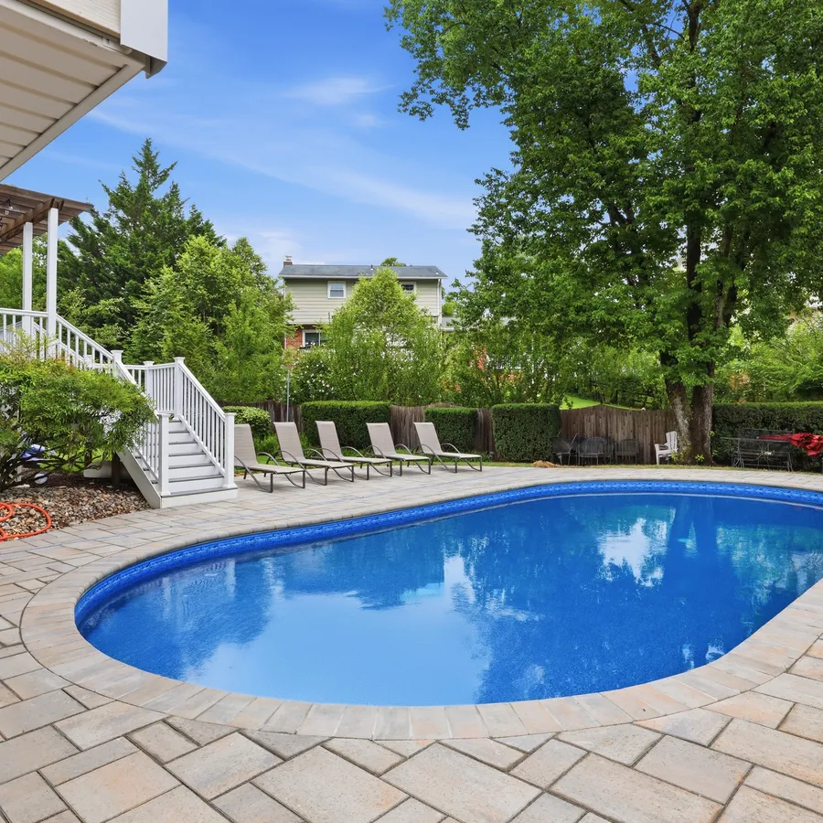 Elevated view of a fully renovated inground pool with loungers on the new paver deck