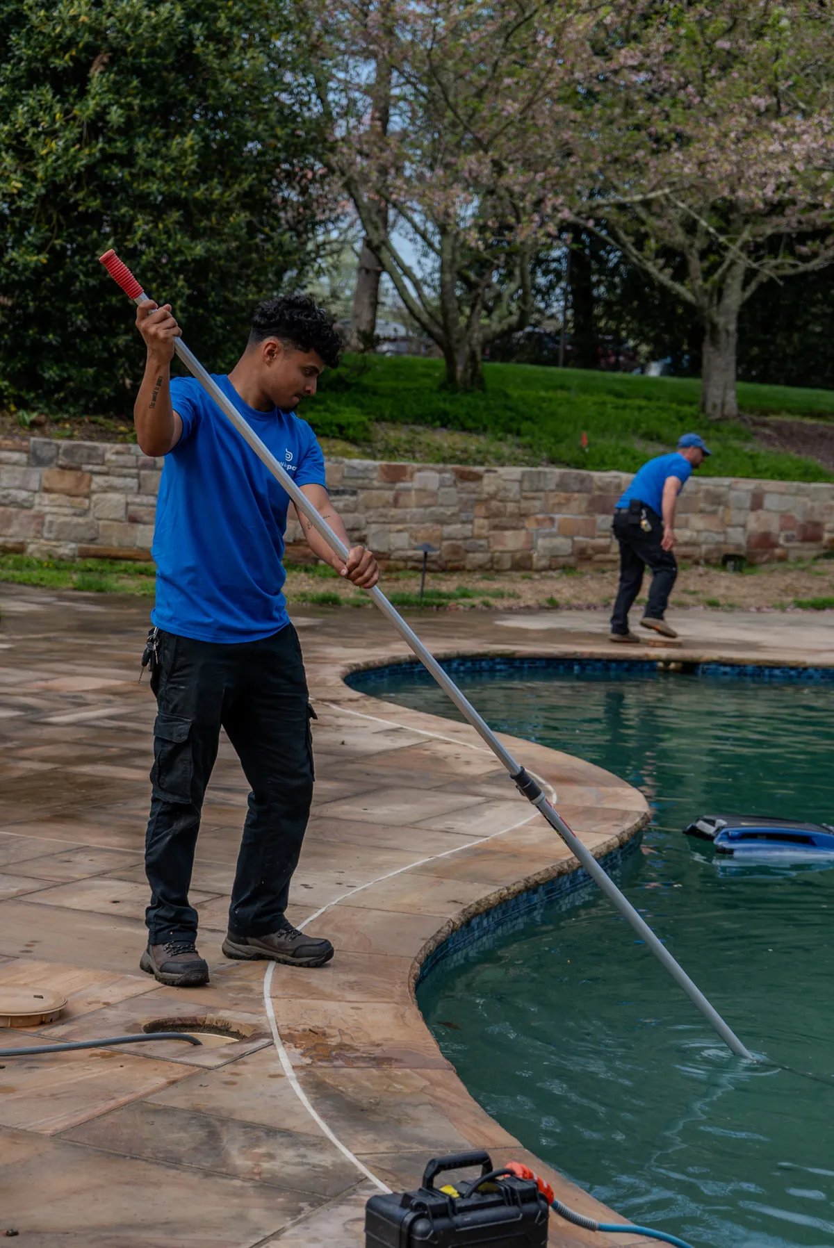 Beltway Pools technician skimming a pool during a routine service visit